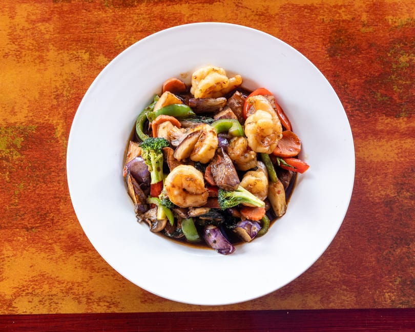 Shrimp and mixed vegetables stir-fry with broccoli, bell peppers, carrots, and eggplant in a dark sauce.